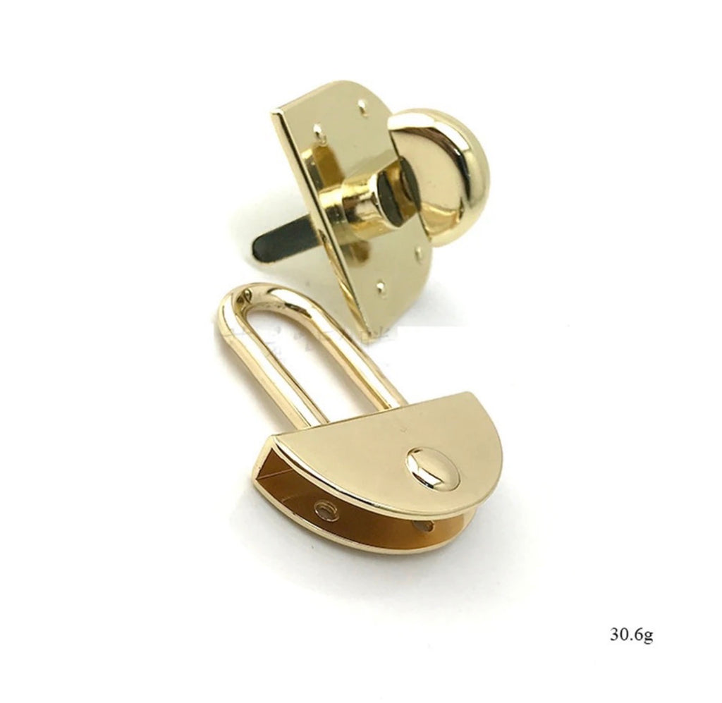 A gold-colored padlock with a semi-circular front and a shackle, shown alongside its lock cylinder and backing plate on a white background. Small text in the bottom right corner reads '30.