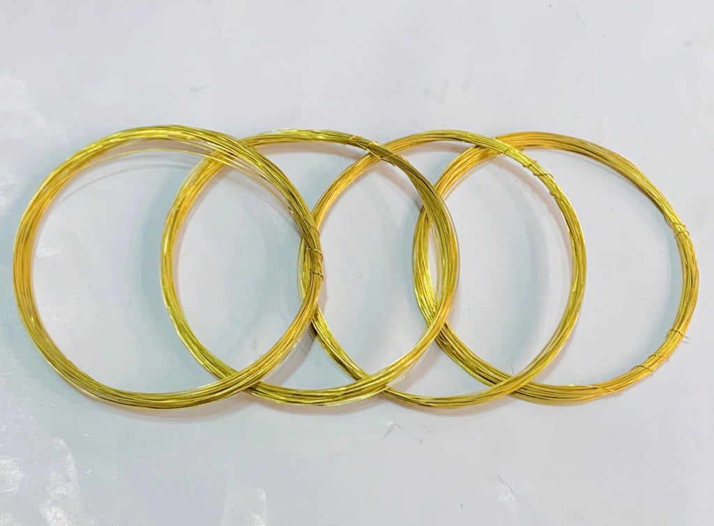 Four coiled gold wire rings of varying sizes arranged in an overlapping pattern on a plain white surface.