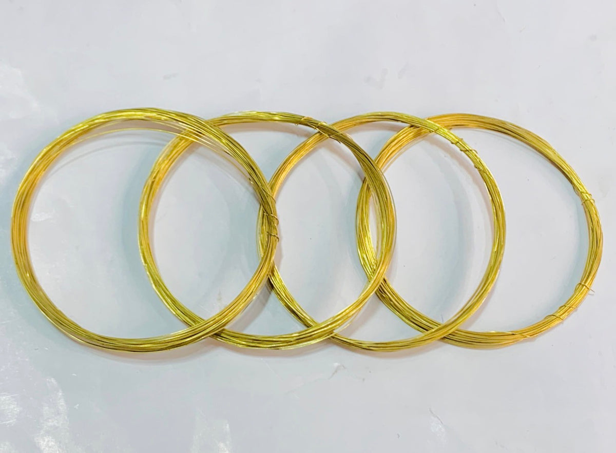 Four coiled gold wire rings of varying sizes arranged in an overlapping pattern on a plain white surface.