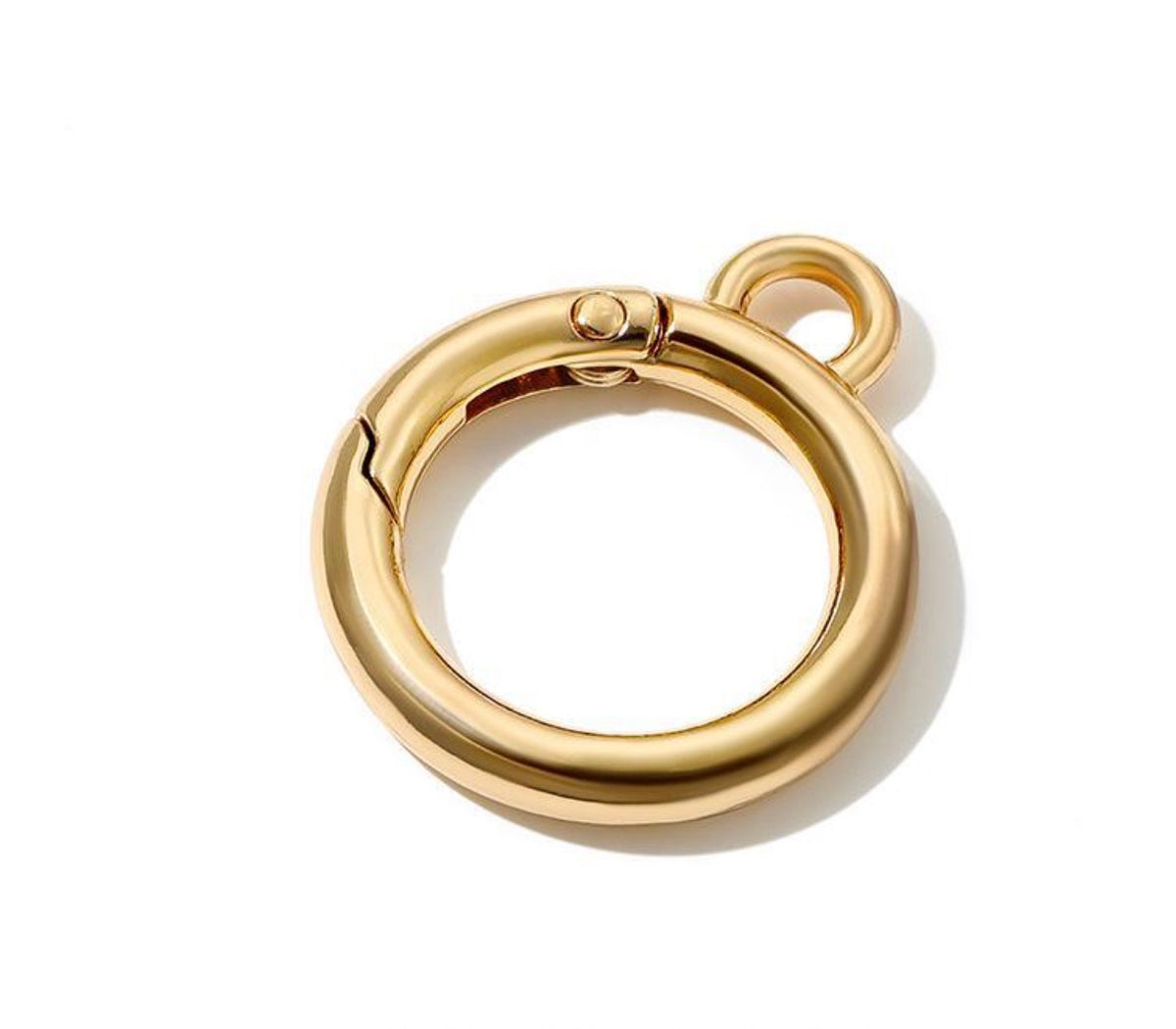 A polished gold-colored metal ring clasp with a small attached loop, shown on a clean white background with a soft shadow.