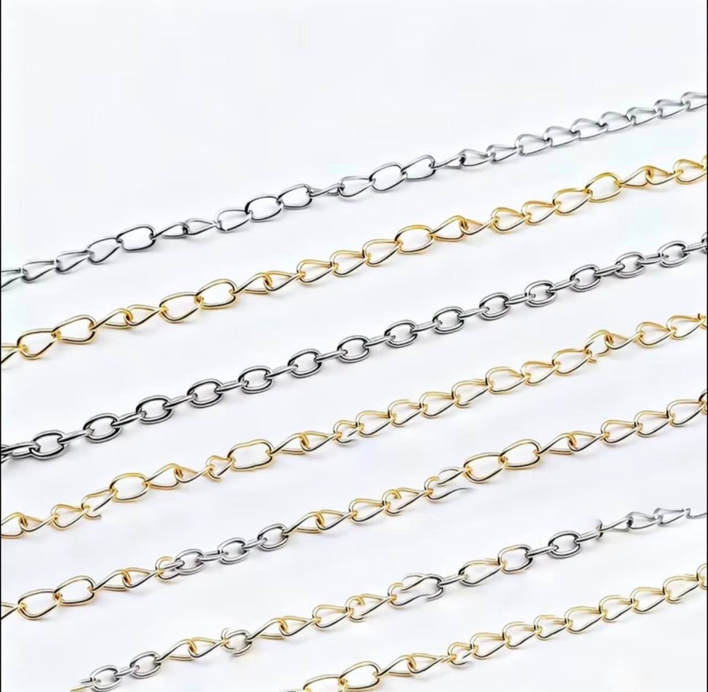 Two parallel strands of elongated oval chain links shown diagonally on a plain white background, one in polished silver-tone metal and the other in polished gold-tone metal.
