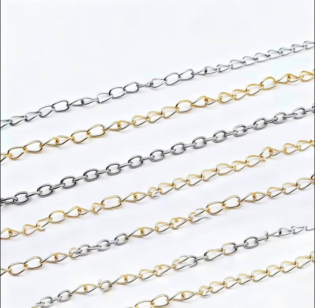 Two parallel strands of elongated oval chain links shown diagonally on a plain white background, one in polished silver-tone metal and the other in polished gold-tone metal.