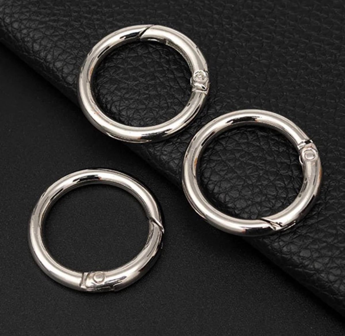 Three silver rings on a black leather surface