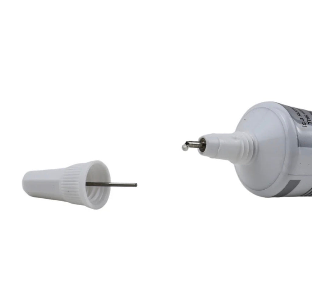 A white plastic applicator tube shown with its cap removed, revealing a metal pin. The cap is placed separately on the left, and the main tube body with the attached pin is shown on the right against a plain white background.
