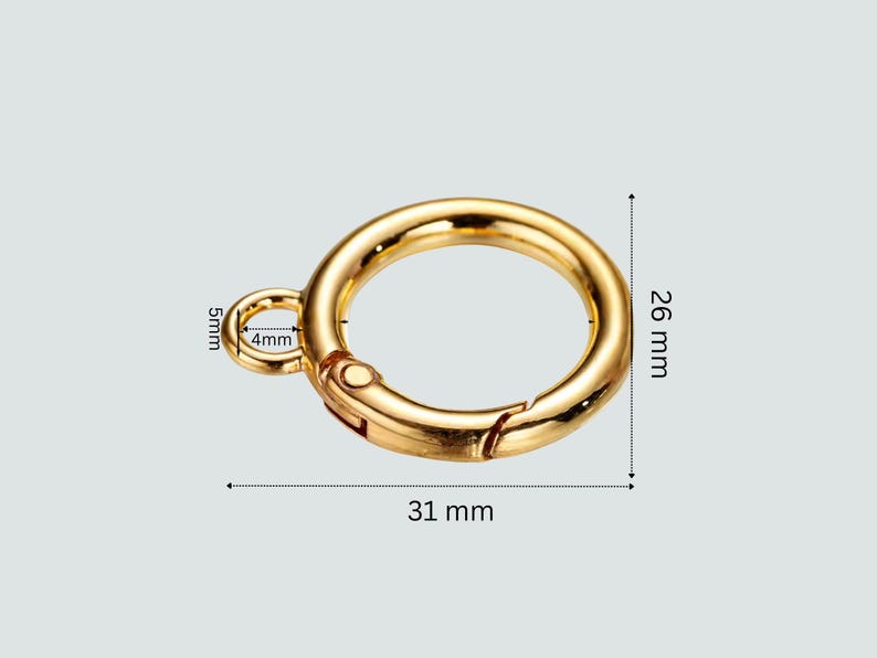 Gold metal ring clasp with dimension annotations showing 31 mm width, 26 mm height, 5 mm left loop, and 4 mm right loop, on a light gray background.
