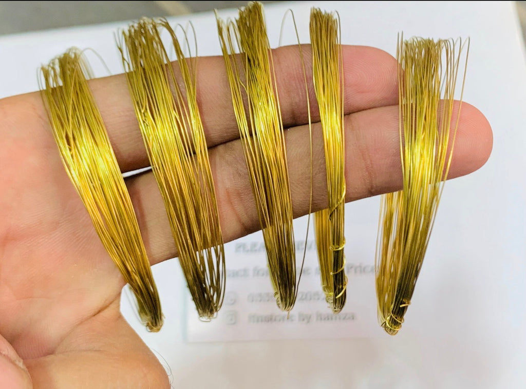 Five small bundles of shiny gold-colored wire held in a person's hand against a white background.