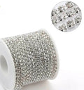 A spool of silver rhinestone trim with a circular inset showing a close-up of the individual clear faceted stones on a white background.